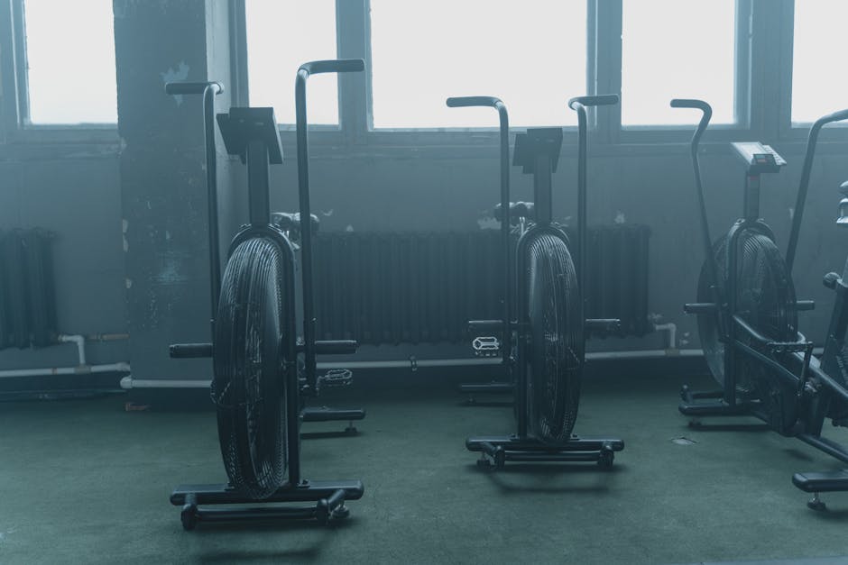 A set of exercise bikes in an empty, dimly lit gym with a muted atmosphere